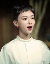 吴谨言端坐于椅中，单手托腮若有所思，复古氛围如电影画面