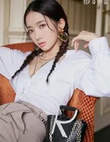 孟美岐慵懒坐于沙发，单臂轻撑，微卷长发自然垂落，一抹红唇绽放温暖笑意，尽显温柔亲和魅力