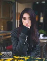 孟美岐身着宽松米白色高领毛衣，伫立于秋日街角，柔和日光轻抚其慵懒卷发，与手中暖黄色花束一同酝酿静谧诗意