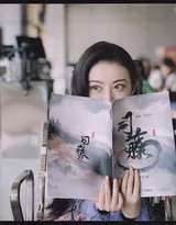 景甜身着白色上衣低头凝神阅读剧本，柔顺黑发自然垂落肩侧