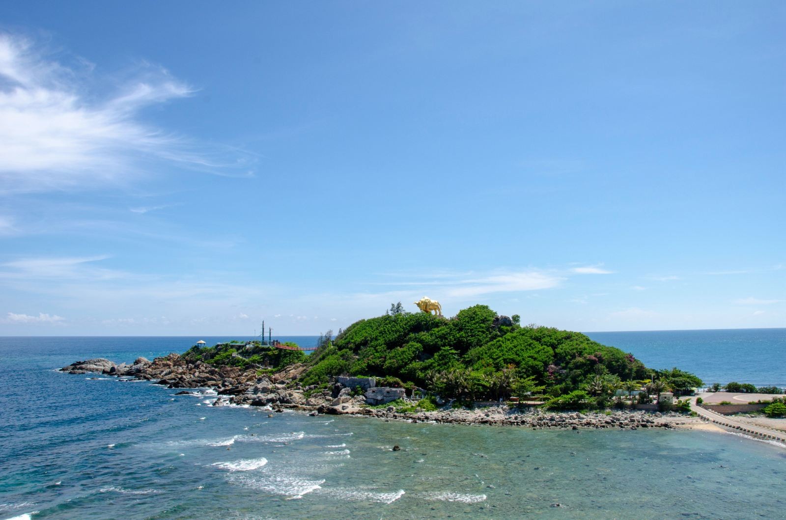 从海面平视翠绿小岛，岛上植被丰茂，礁石环绕，海水清澈见底，充满原始海岛风情