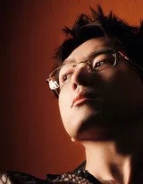 李现放松站立，双手自然下垂，背心展现宽阔肩部，眼镜后的目光温和坚定，整体散发从容气场