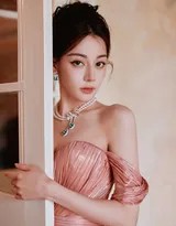 迪丽热巴身着流光粉色长裙侧身而立，裙摆如花瓣般铺陈于地，眼眸低垂间流露出温柔静谧的气息