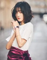 微风拂过，王梓薇的短发轻轻飘动，她低头浅笑，紫色裙摆随风摇曳，尽显温柔恬静的少女气息