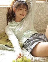 少女蜷腿坐在沙发一角，手托下巴眼神俏皮望向镜头，如同刚分享了一个小秘密