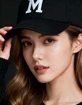 柔光中女生微抬帽檐，M标志清晰可见，面容在明暗交错间流露都市女性的从容气质