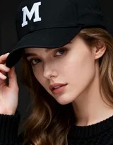 暖色调光影下，戴M字母帽的女生倚靠沙发，展现自信浅笑，时尚态度在静谧空间中自然流淌
