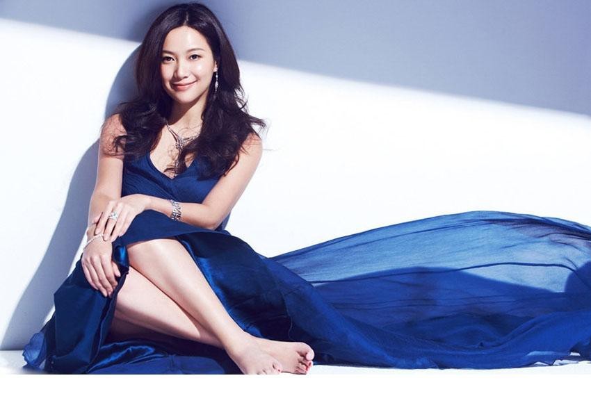徐静蕾身穿黑色深V连衣裙，倚靠于桌旁，身体曲线流畅，低调的性感与强大气场在光影交织中融合。