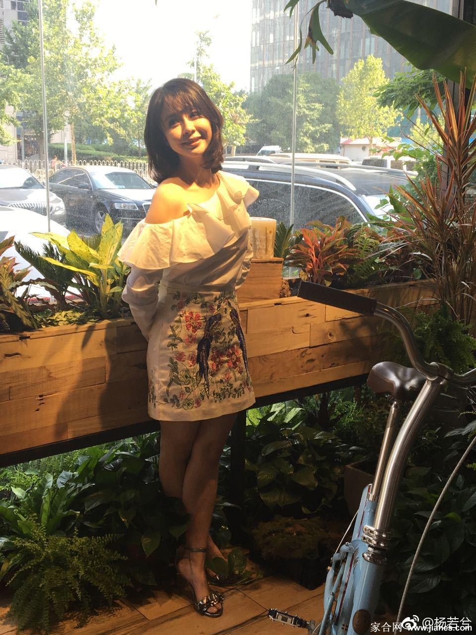 轻抚秀发，杨若兮展露浅笑，修长双腿在丝袜包裹下与高跟鞋构成完美线条
