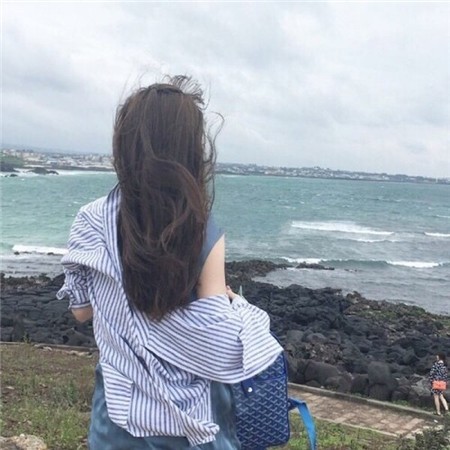 细雨朦胧的街头，一个撑着透明雨伞的女孩背身行走，水洼倒映出她模糊的身影与都市霓虹，孤独而疏离。