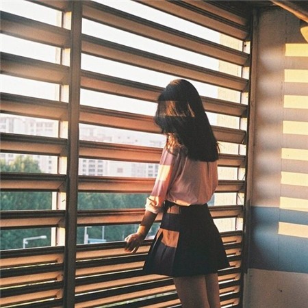 纯白窗帘被风轻轻吹起，女孩背对镜头站在窗前，微光勾勒出她的身形，背影干净而脆弱，仿佛一个易碎的梦境。