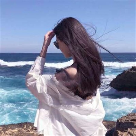海岸线的沉思：人物独自立于夜晚的海边，身影被城市与节日的光晕温柔包裹，海浪轻抚沙滩，画面弥漫着对过往的怀念与静谧的治愈力。