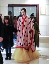 倪妮与现场背景互动，粉色身影在深色环境中格外突出，宛如一幅现代时尚画作