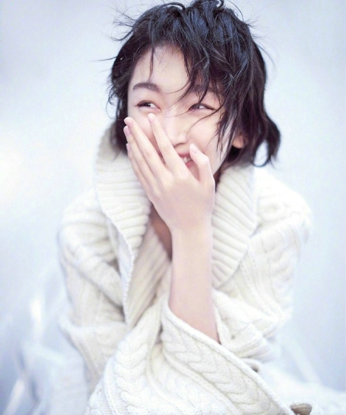 周冬雨置身于街头背景，低头浅笑，瞬间捕捉到清新自然的少女气息
