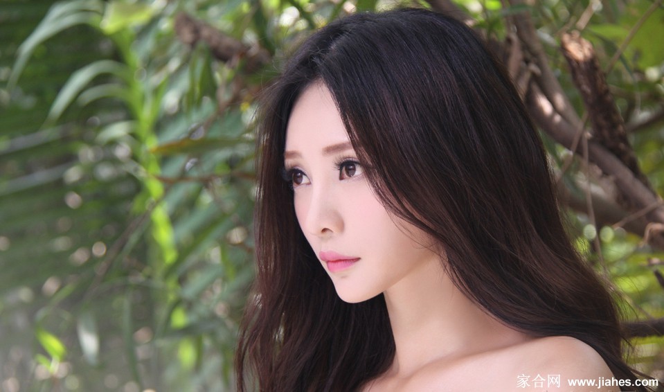 柳岩在镜头前展露自信微笑，白裙勾勒出曼妙曲线，身后光影斑驳，氛围静谧美好