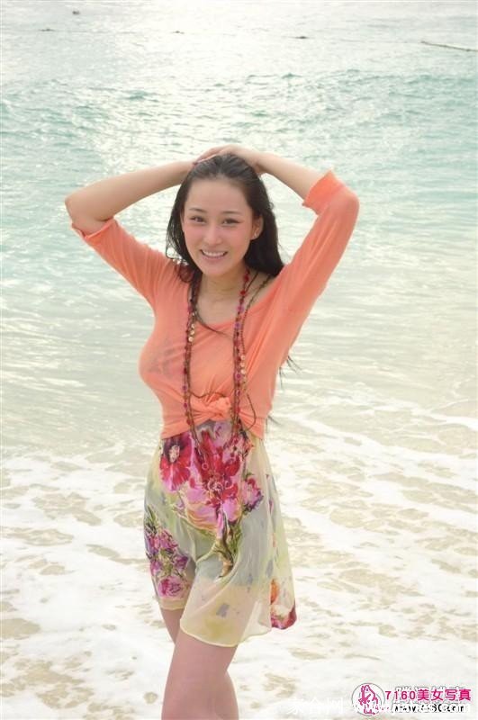 她仰头闭目感受海浪的轻抚，水润的红唇与潮湿的肌肤在自然光下呈现出极具生命力的美感。
