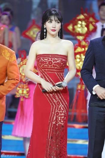 春晚舞台上韩红一身红衣激情演唱，管彤身穿礼服在一旁微笑主持的现场剧照