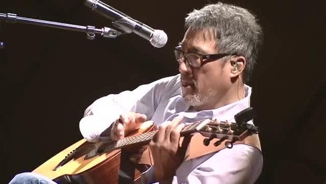 李宗盛在录音室工作照，专注于弹奏吉他的特写